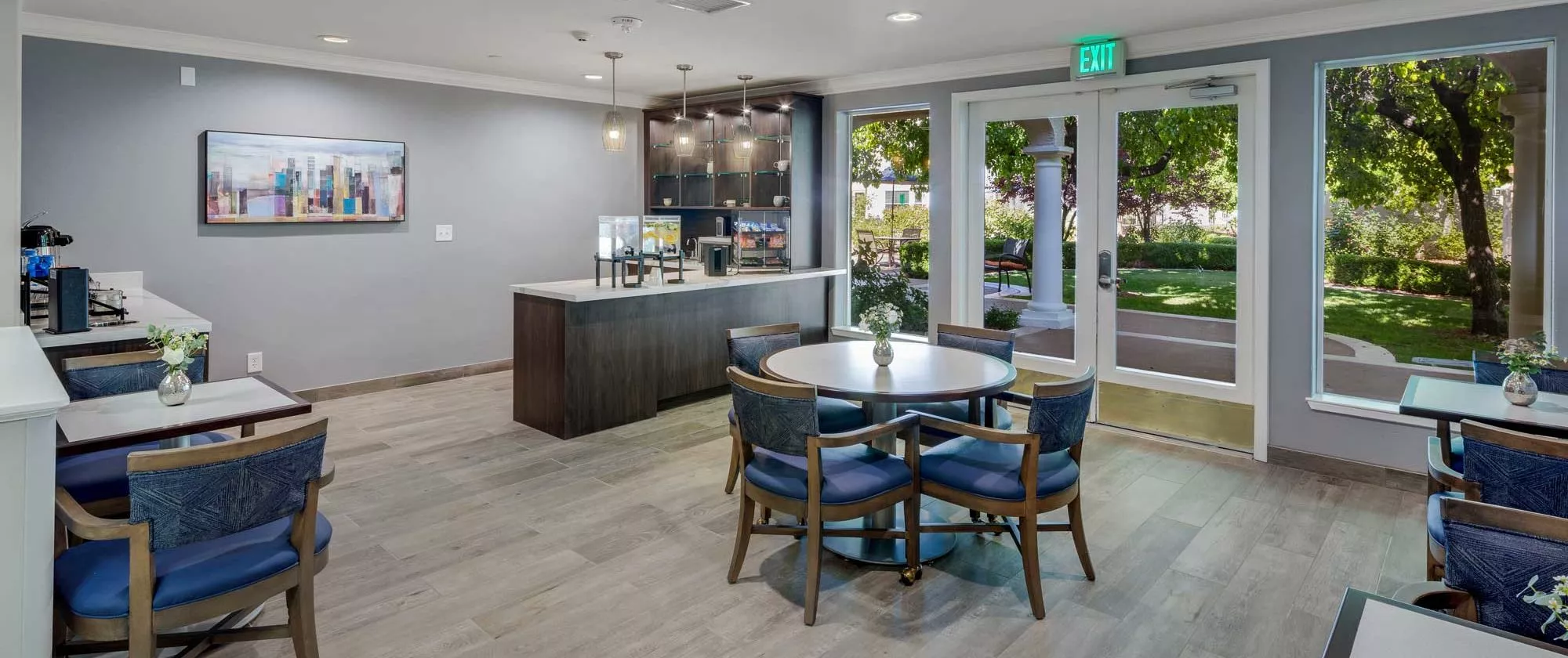 A modern kitchen area featuring a round table with chairs, sophisticated lighting, and sleek cabinetry.