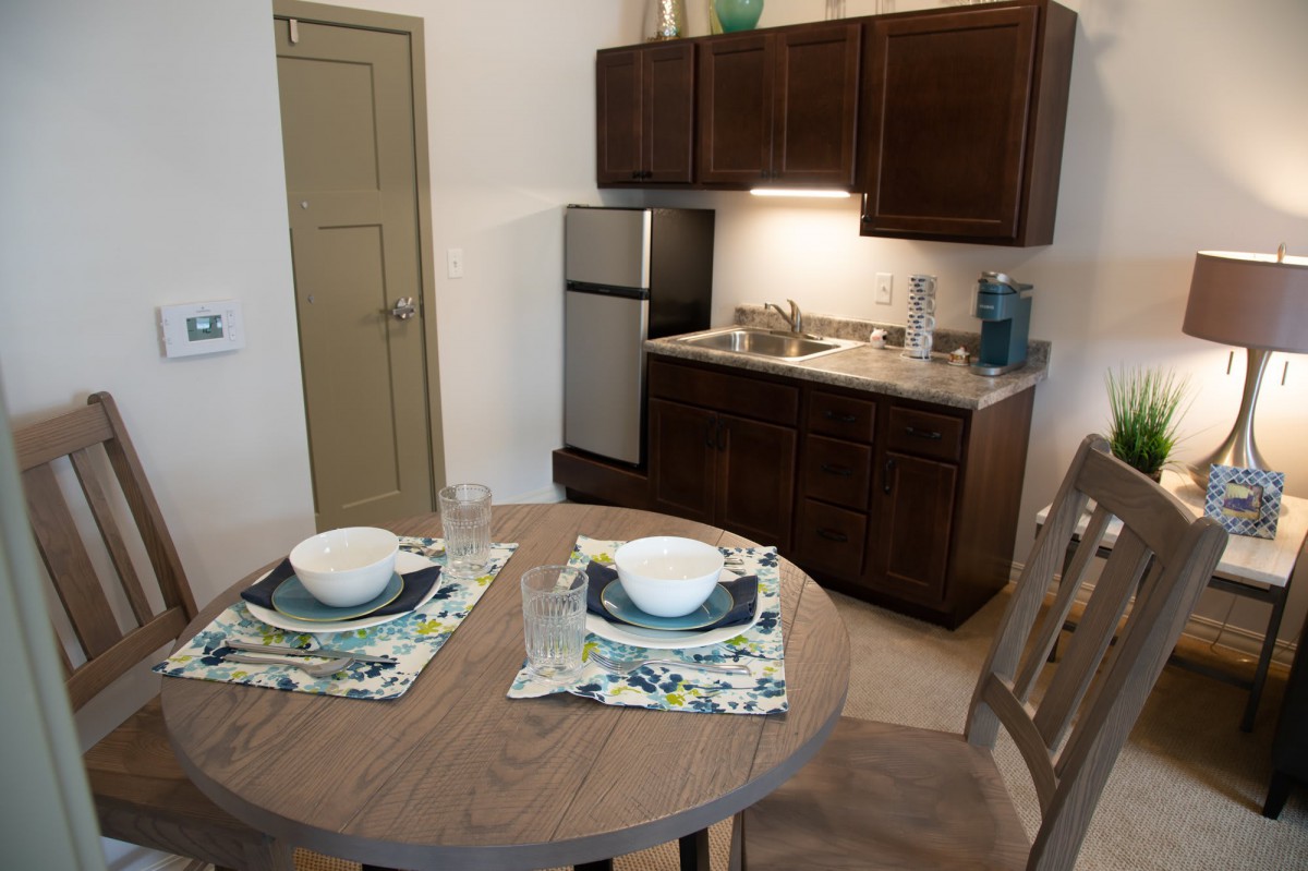 A small kitchen with a dining area featuring a round table set for two.