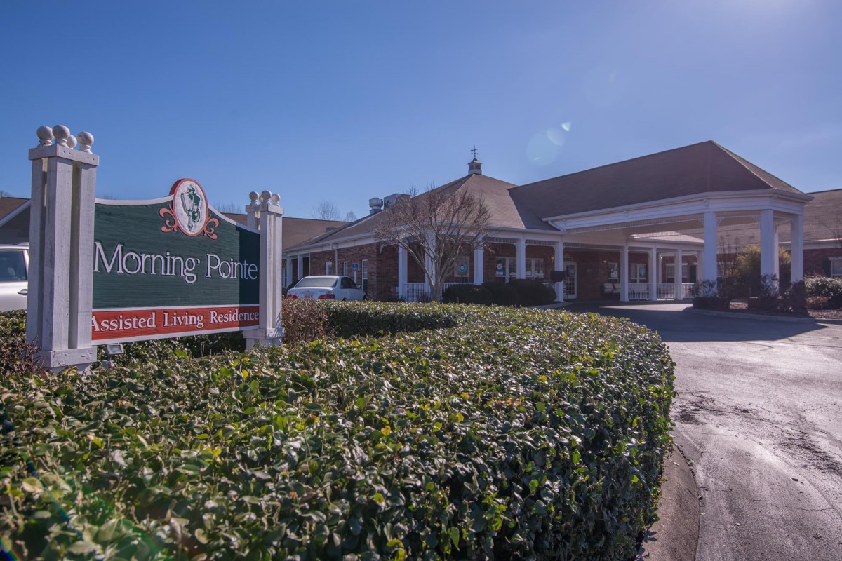 A building entrance with signage and well-maintained landscaping on a clear day.