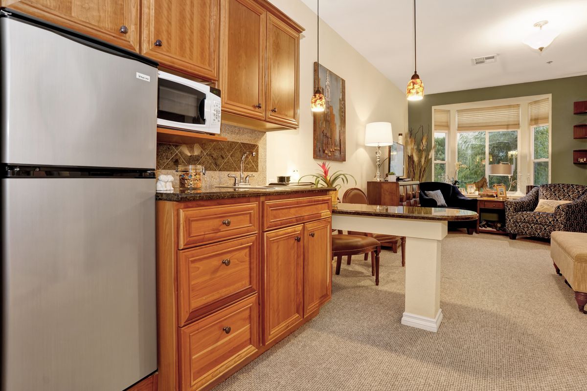 A cozy kitchen with wooden cabinets and stainless steel appliances, seamlessly opening into a comfortable living area.