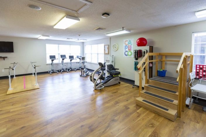 A well-lit gym with various exercise equipment including treadmills, stationary bicycles, and exercise balls.