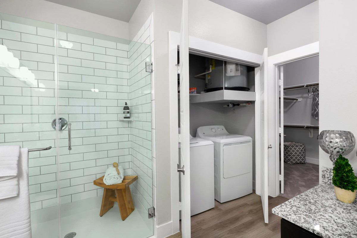 A modern bathroom and laundry area with a shower, washer, and dryer.