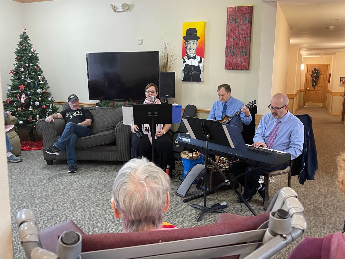 A small group of musicians performing in a living room setting for an audience.