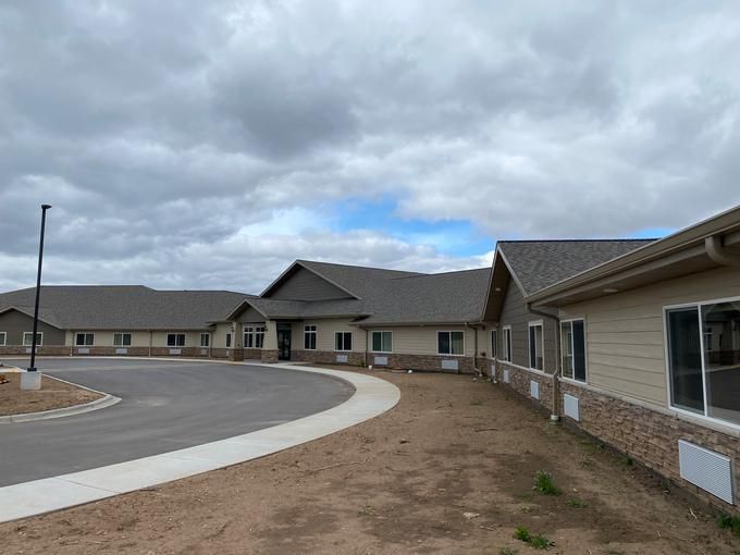A newly constructed building under a cloudy sky with a surrounding parking area.