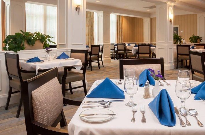 An elegantly set dining area with neatly arranged tables and blue napkins.