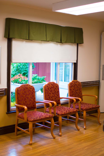 A cozy waiting area featuring three upholstered chairs and a view of greenery outside.