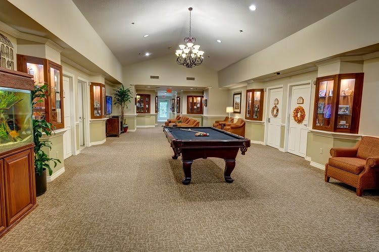 A spacious lobby area featuring a pool table, comfortable seating, and a decorative chandelier.