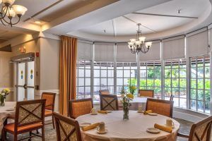 An elegant dining room with a round table, comfortable chairs, and a chandelier.