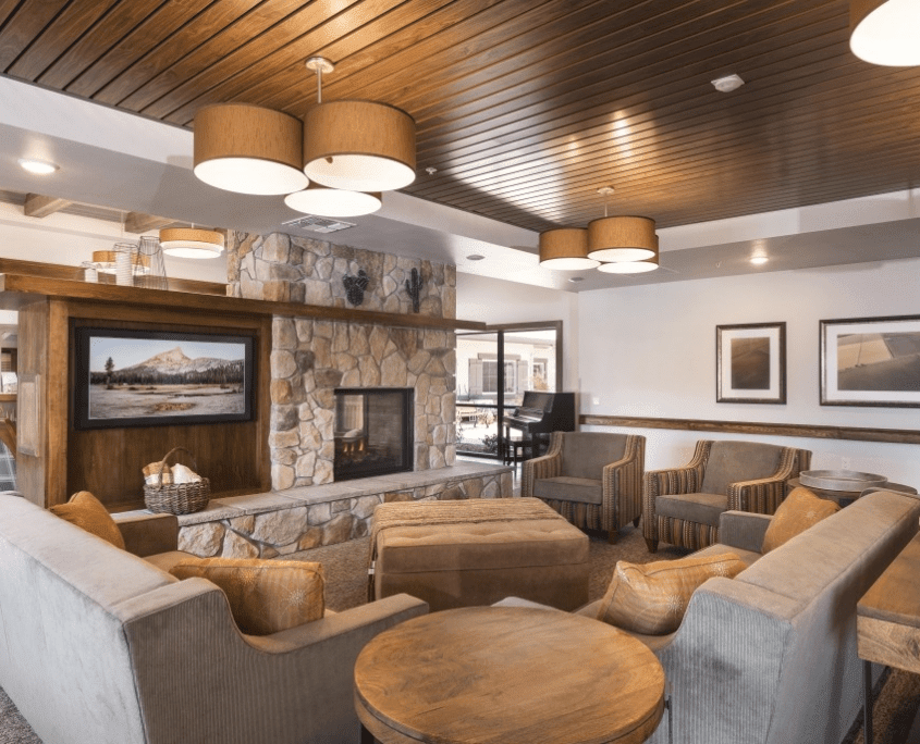 A cozy living room with a modern interior design featuring a stone fireplace and comfortable seating.