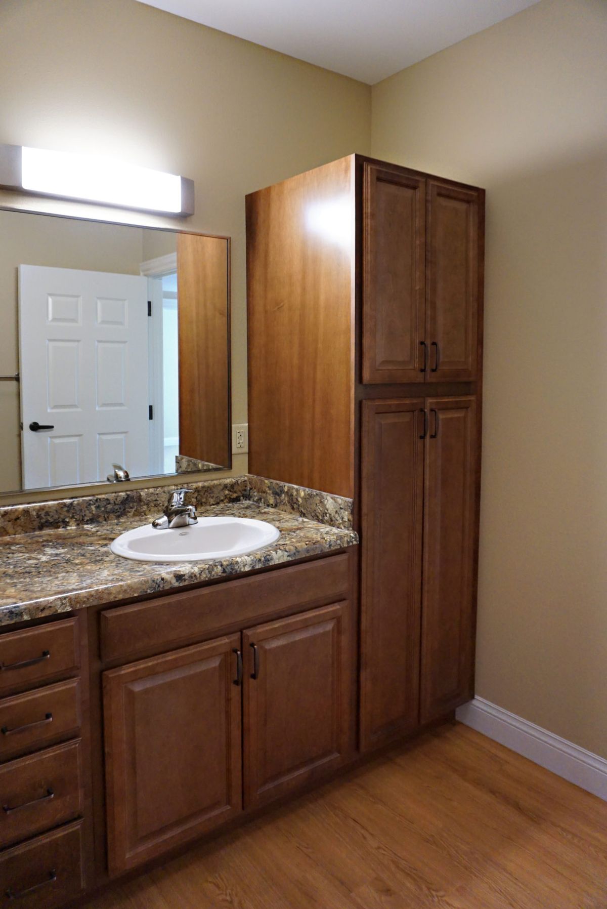 A bathroom vanity with a wood cabinet and marble countertop.
