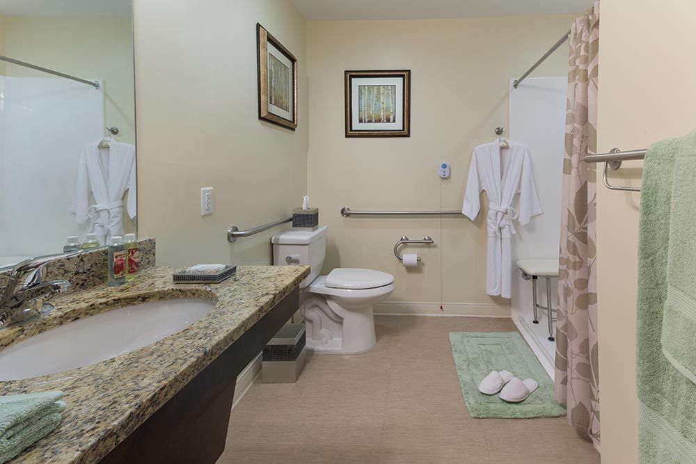 A clean and well-decorated bathroom featuring a toilet, sink, and shower area with bathrobes and towels.