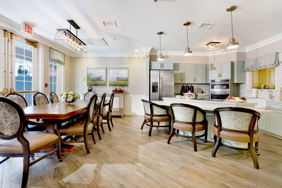 A modern kitchen and dining area featuring elegant furniture, wood flooring, and stylish lighting fixtures.