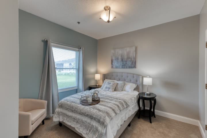 A cozy bedroom with a neatly made bed, bedside tables, and a window offering natural light.