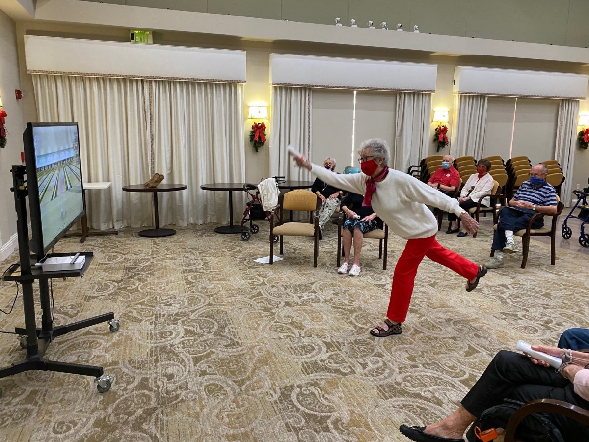 A group of elderly individuals participating in an indoor exercise session focusing on balance and movement.