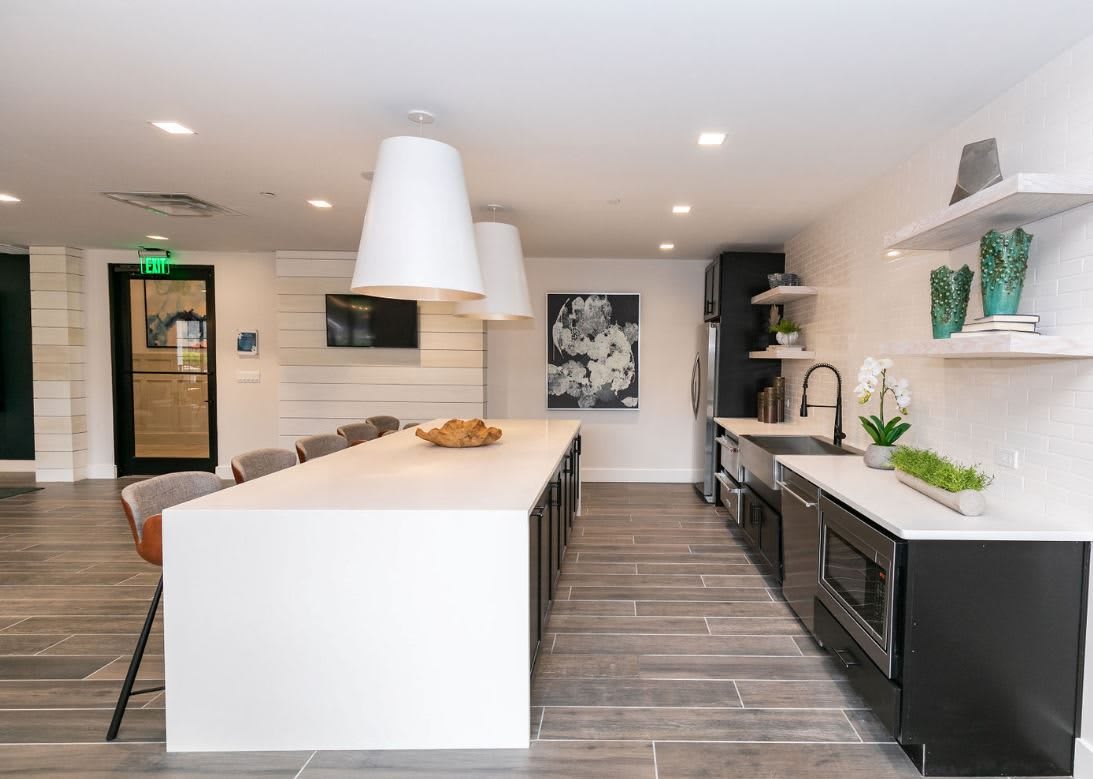 A modern kitchen with a large island, pendant lighting, and stainless steel appliances.