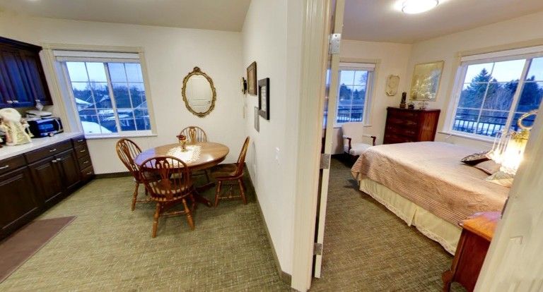 A view of a cozy dining area adjacent to a bedroom with classic wooden furniture.
