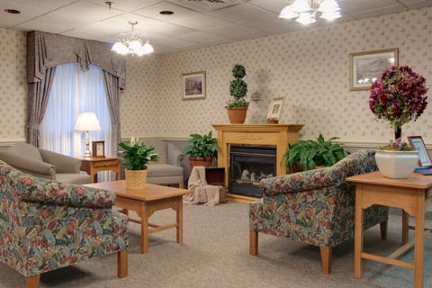 A cozy living room with comfortable seating, a fireplace, and decorative plants.