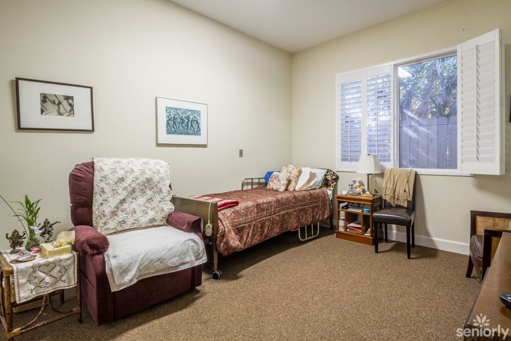 A cozy bedroom with a single bed, comfortable chair, and wall artwork.