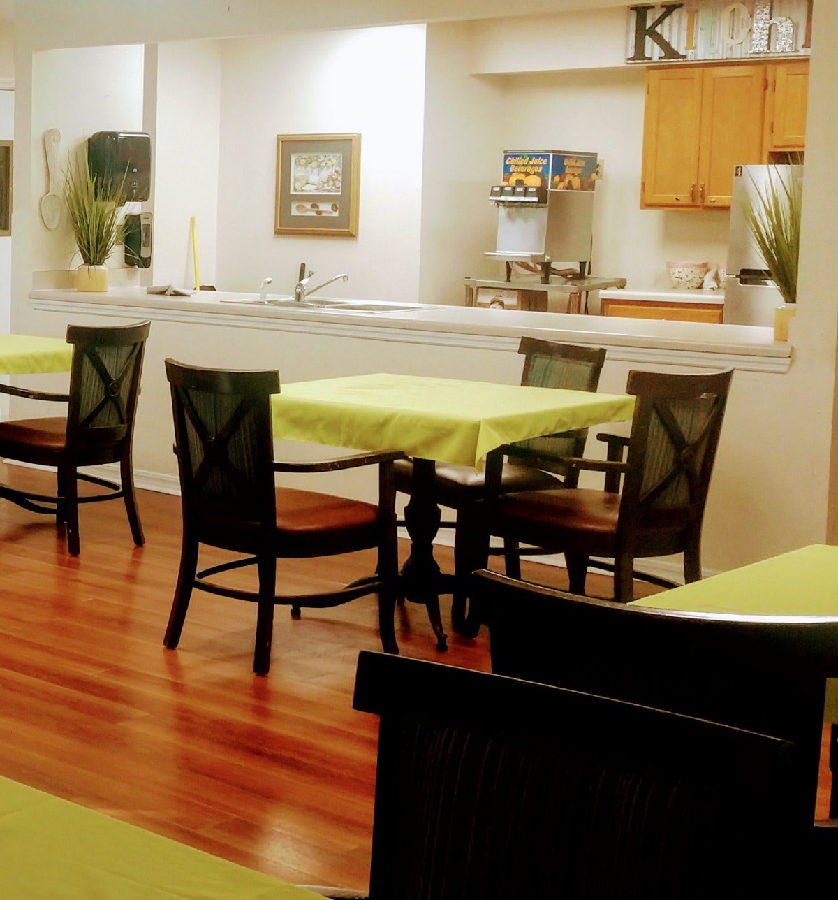 A cozy dining area with tables and chairs, adjacent to a kitchen.