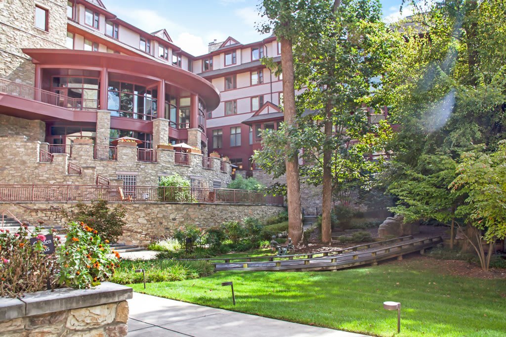 A scenic view of a building with an elegant garden and lush greenery.