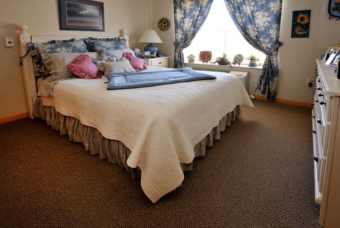 A cozy bedroom with a large bed, floral curtains, and decorative pillows.