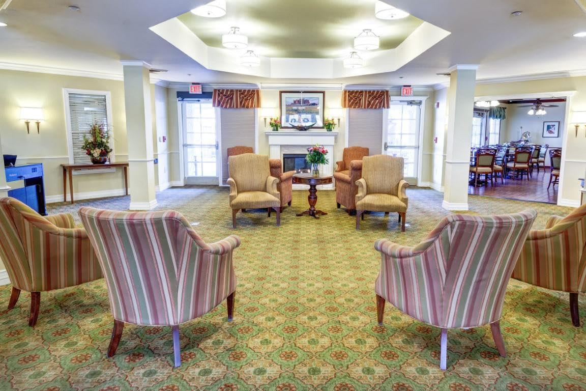 A cozy lounge area with armchairs arranged around a fireplace.