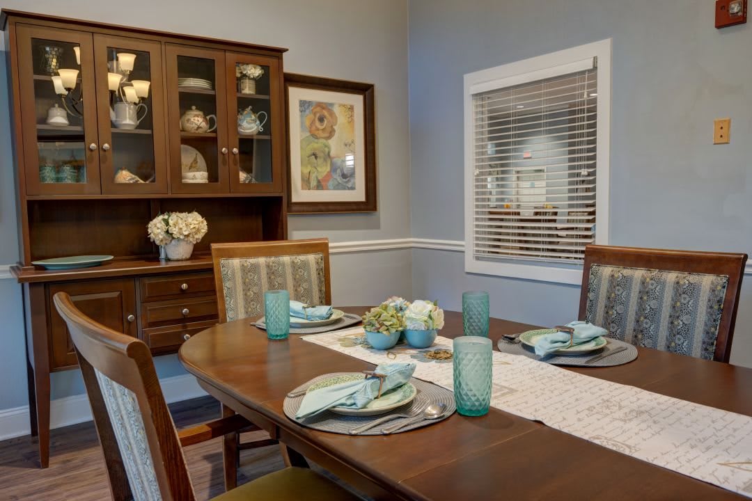 A well-decorated dining room with an elegant table setting and a wooden cabinet displaying dishes.