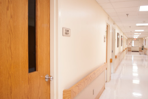 A quiet corridor in a hospital with a door leading to a patient room.