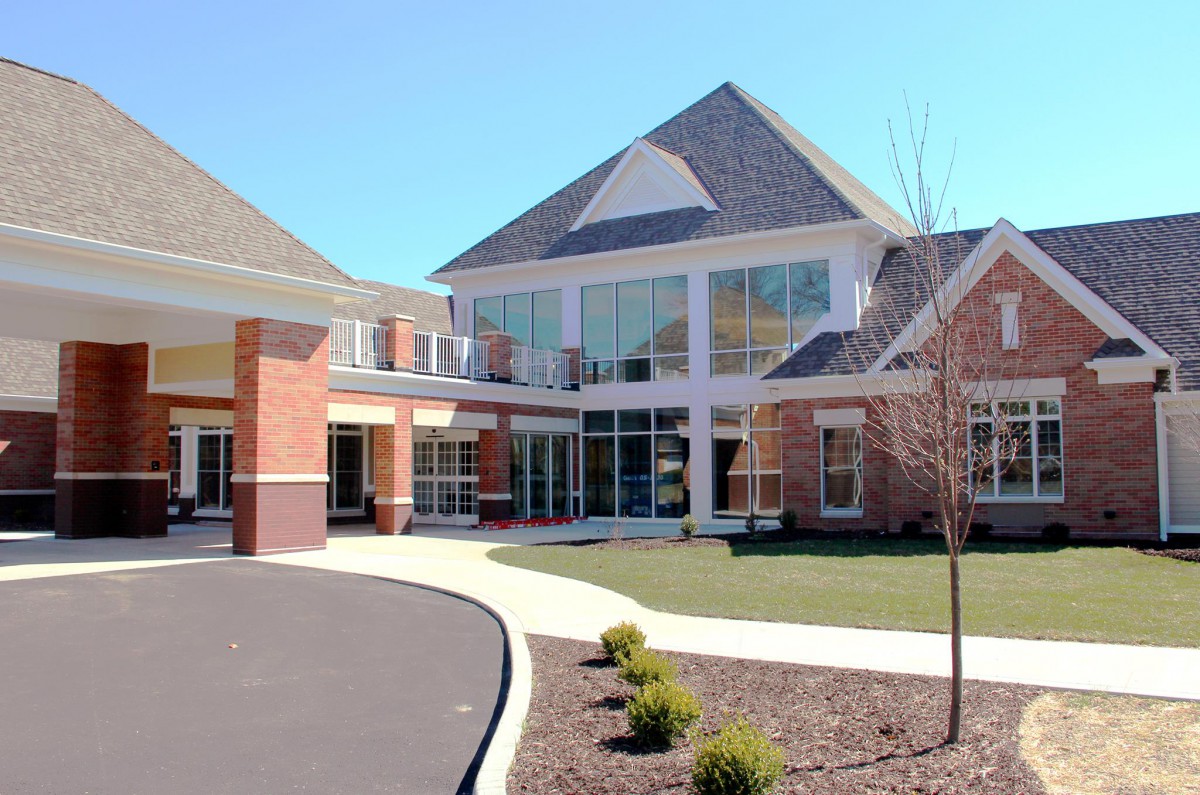 A modern brick building with large windows and a landscaped driveway.