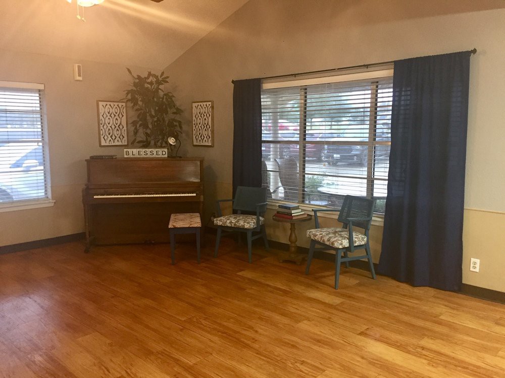 A cozy room with a piano and chairs by the window.