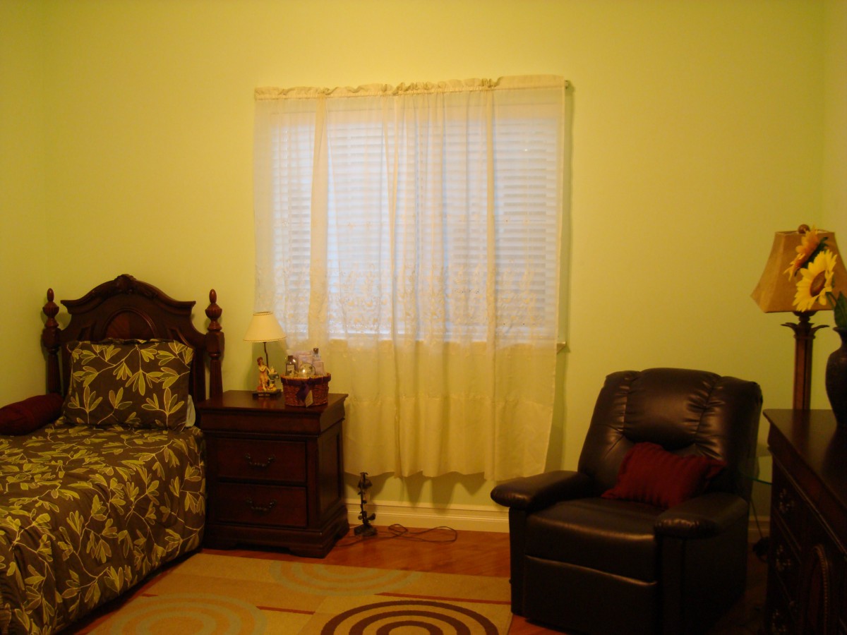 A cozy living room with a sofa, armchair, and curtained window.