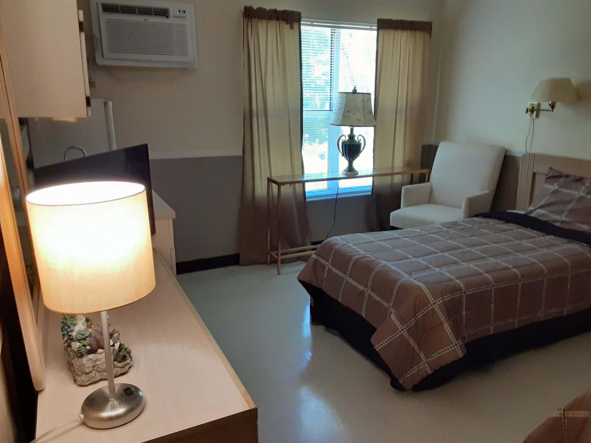 A cozy bedroom with a bed, chair, and lamps.