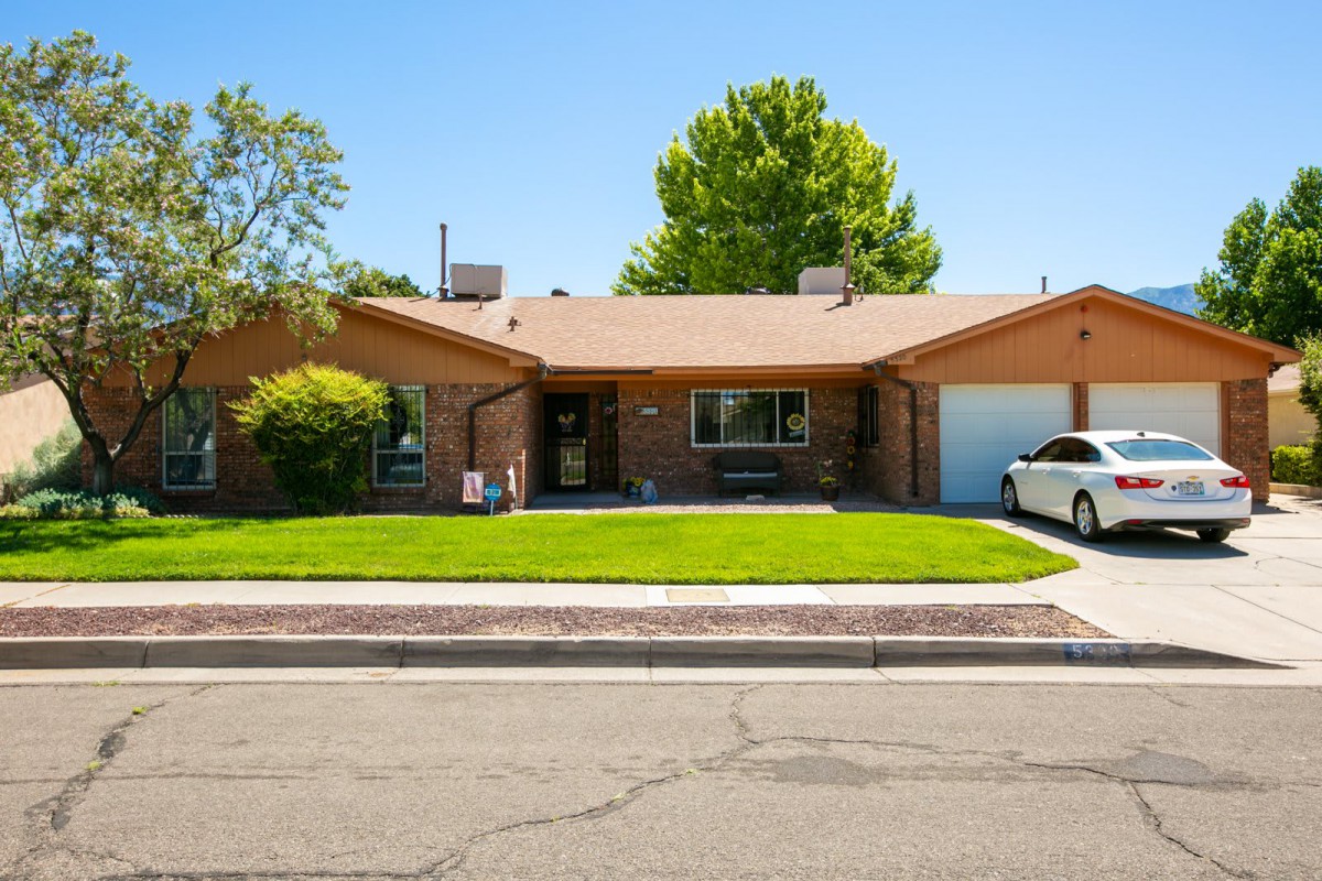 A suburban brick house with a well-maintained lawn and attached garage.