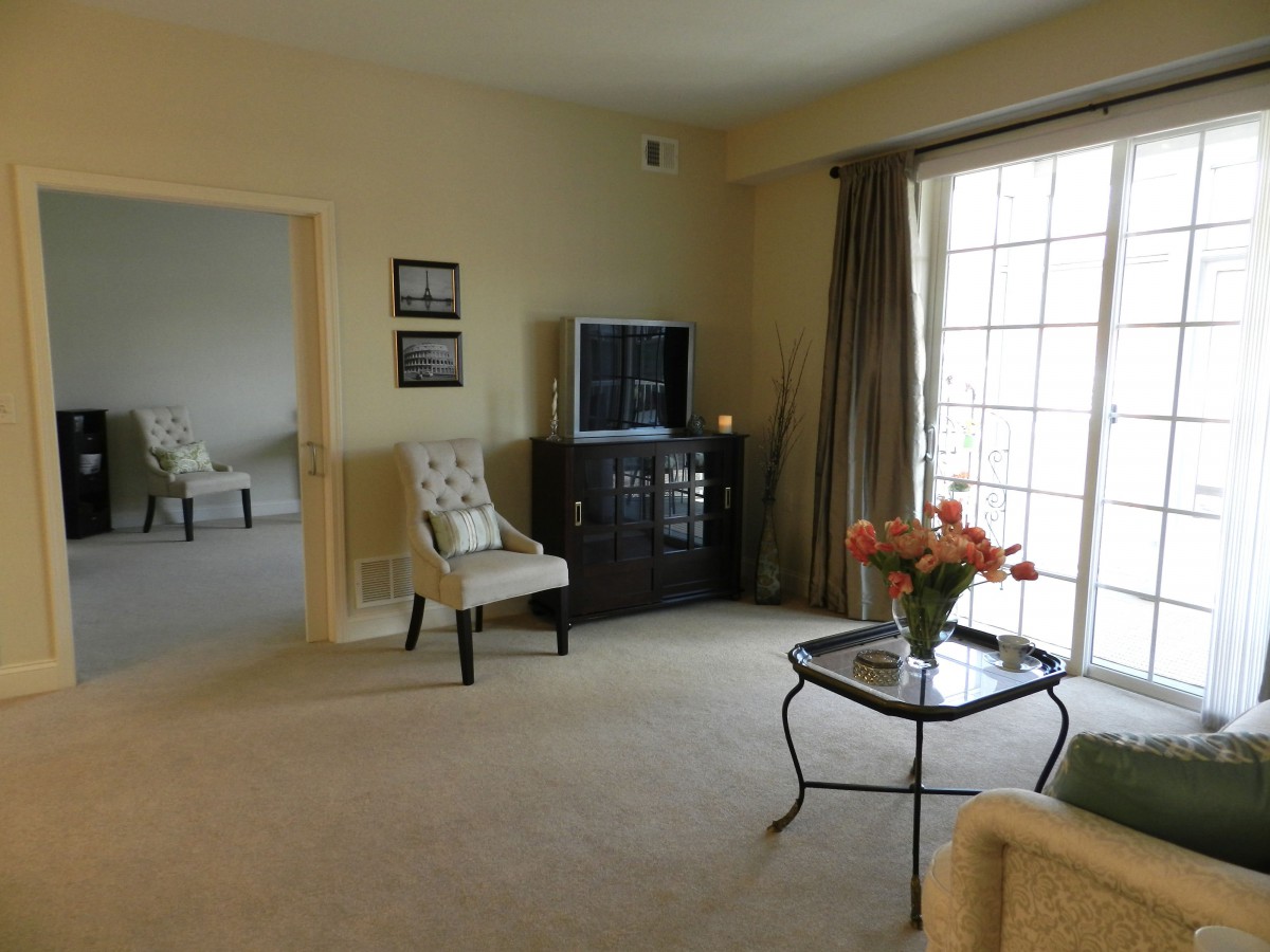 A cozy living room with a television, chairs, and a coffee table adorned with flowers.