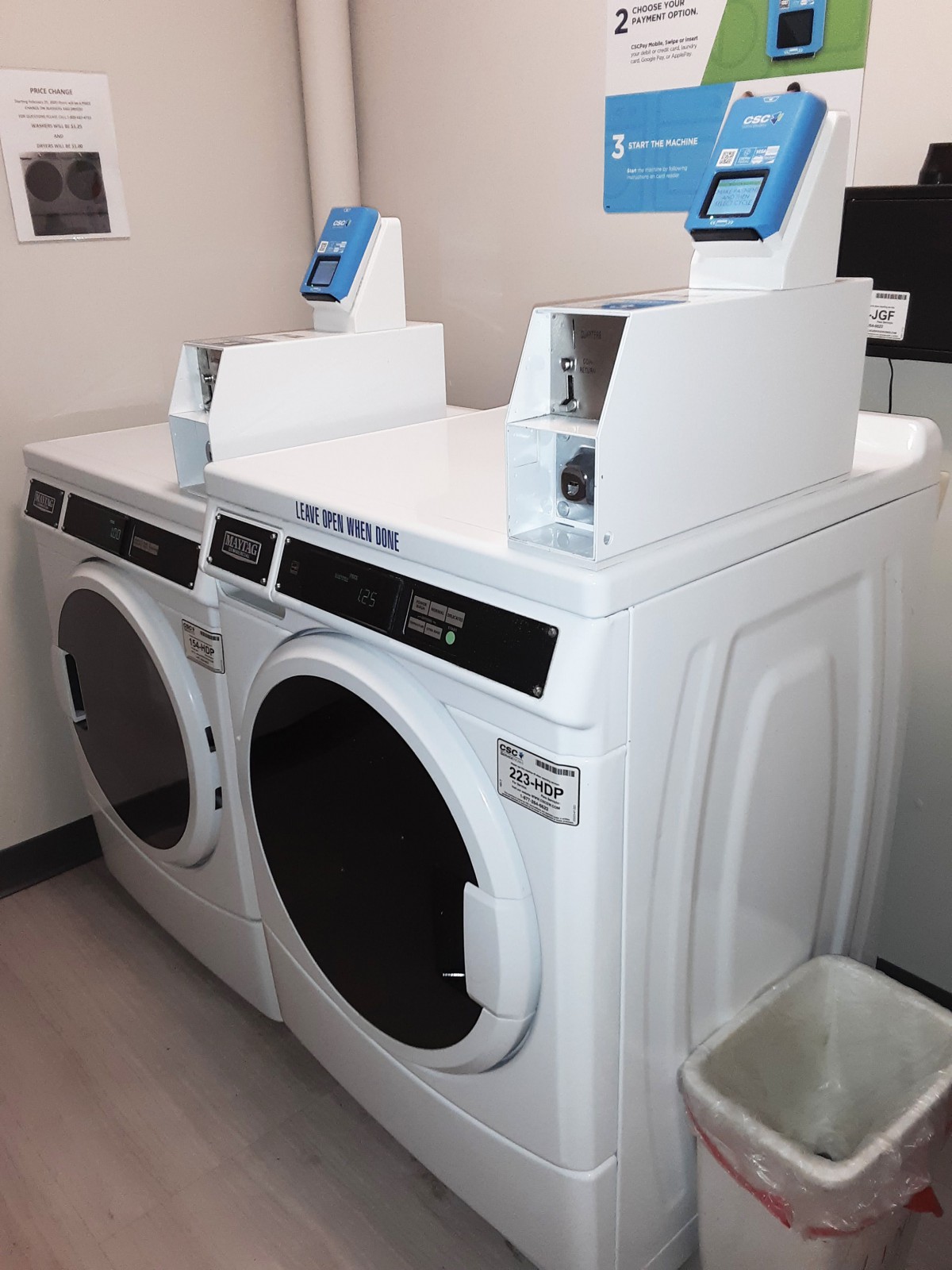 A pair of white washing machines in a laundromat.