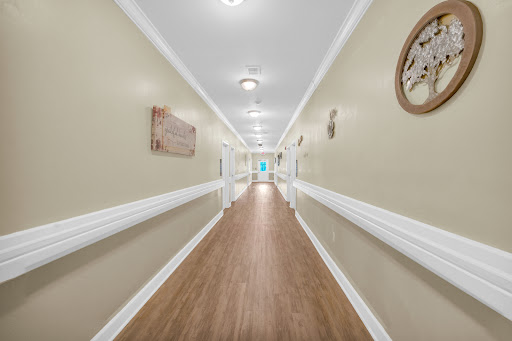 A well-lit hallway featuring neutral-colored walls and wooden flooring, creating a welcoming atmosphere.
