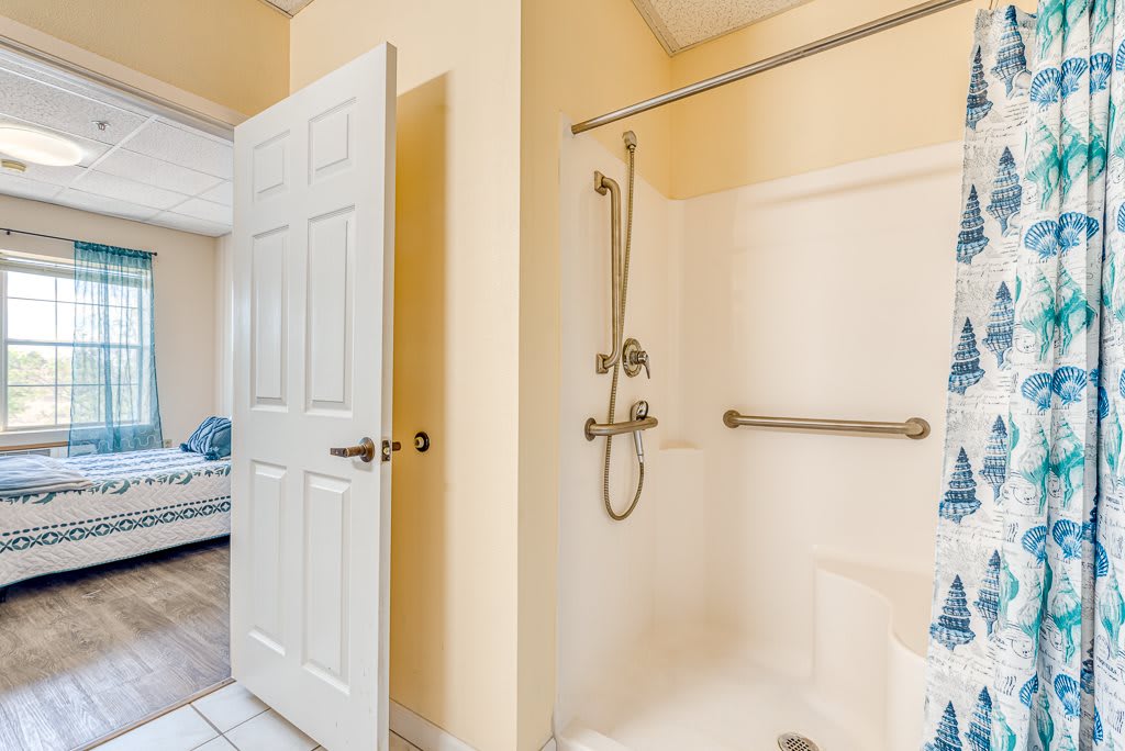 A bathroom with a walk-in shower featuring a grab bar and showerhead.