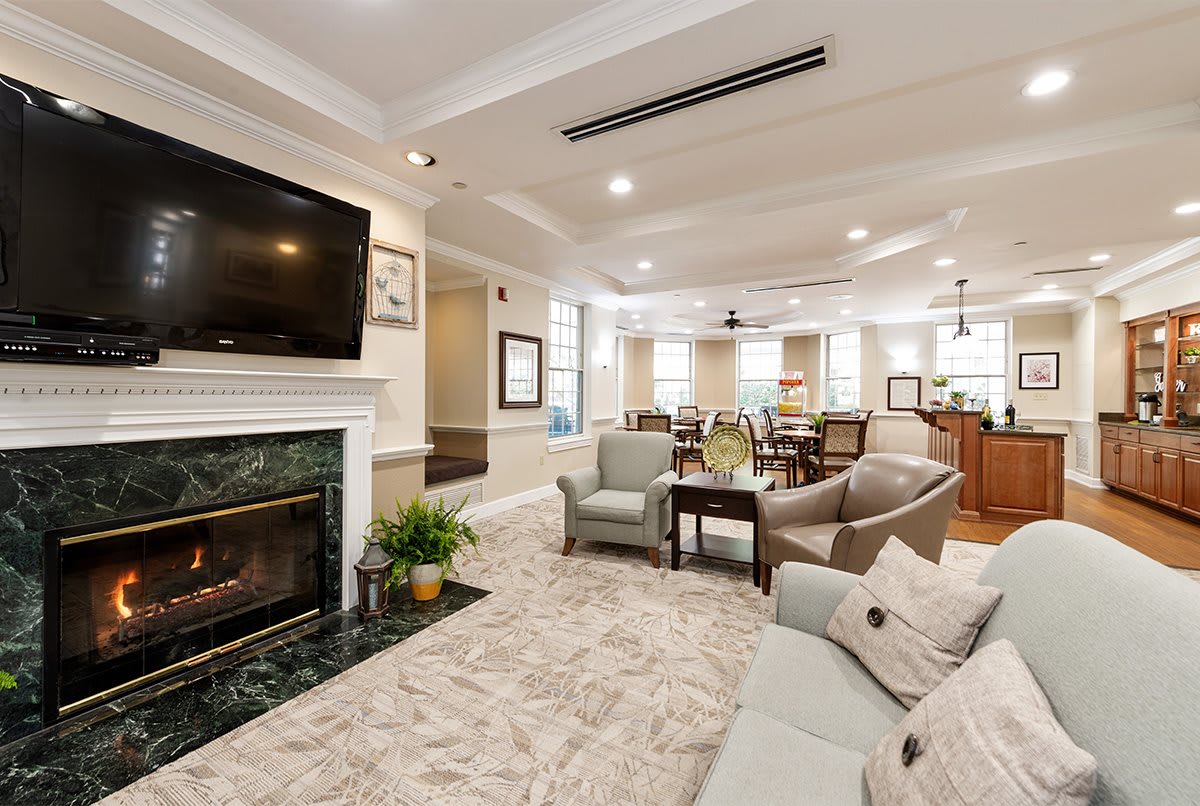 A spacious and elegantly designed living room featuring a fireplace, large TV, comfortable sofas, and a coffee table.