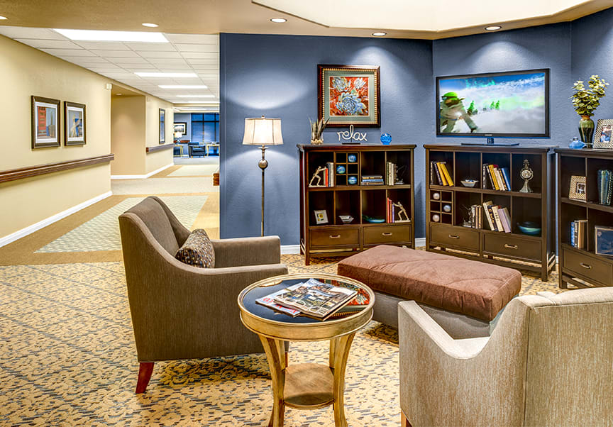A cozy lobby with comfortable seating, bookshelves, and warm lighting.