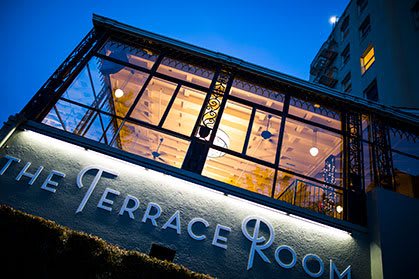 The Terrace Room building glows with warm lighting during the evening.