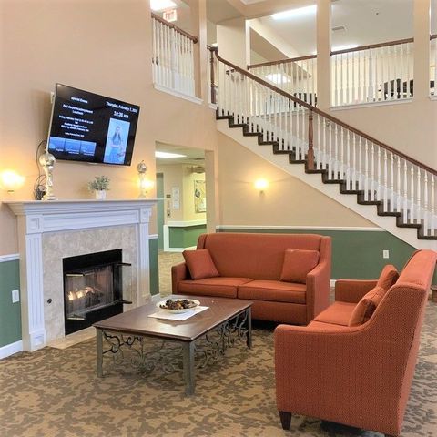 A cozy living room with a fireplace, comfortable sofas, and a television mounted above.