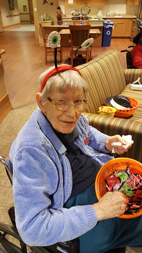 An elderly woman joyfully enjoying some treats in a cozy indoor setting.