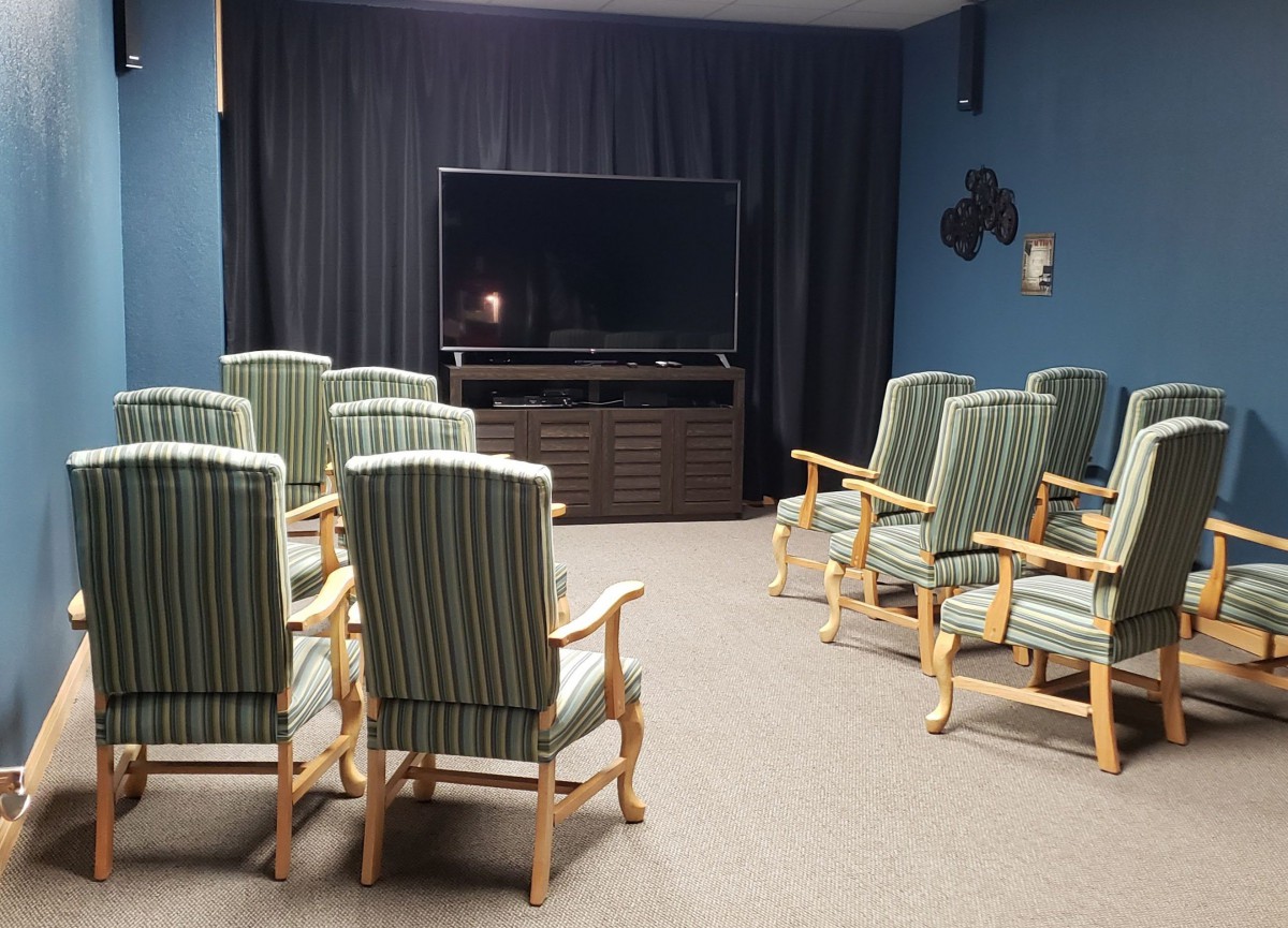 A cozy home theater setup with striped armchairs facing a large television.