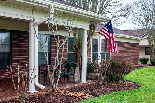 A welcoming house with a front porch featuring an American flag and well-maintained landscaping.