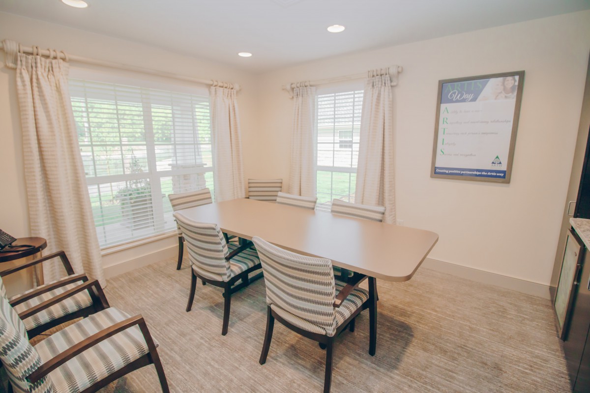 A bright and airy conference room with a table and chairs, featuring large windows and neutral decor.