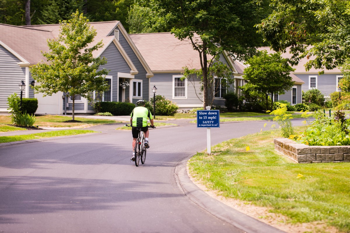 A cyclist rides through a suburban neighborhood on a sunny day.