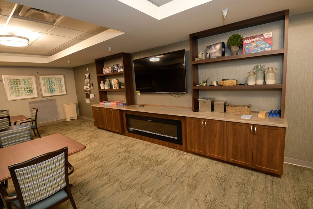 A modern living room with a large television and built-in wooden shelves filled with books and decorative items.