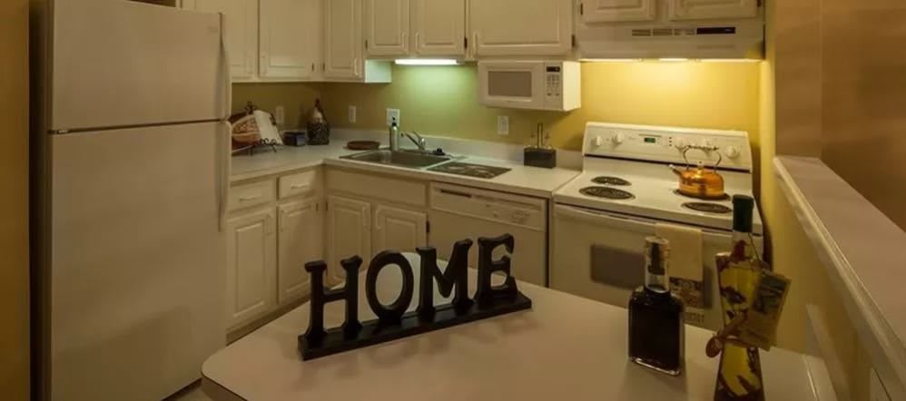 A cozy kitchen with 'HOME' decor on the countertop and various appliances.