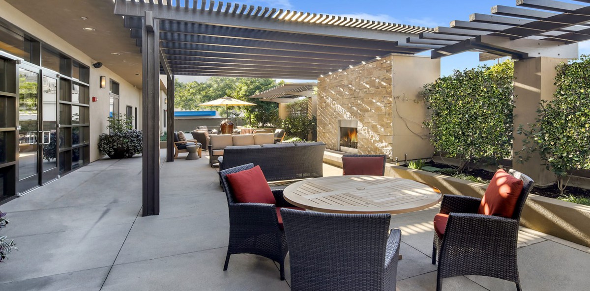 A sunny outdoor patio with comfortable seating and a pergola.