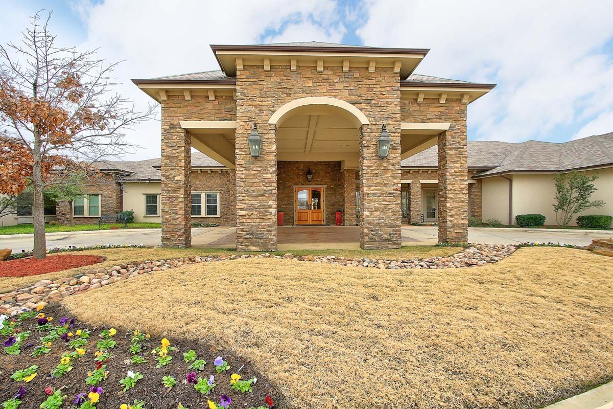 A brick residential house with a grand entrance and landscaped yard.